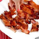Air fryer bacon with hand grabbing a piece